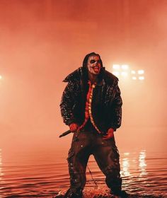 a man standing on top of a body of water wearing a mask and holding a knife