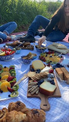 a woman sitting on the ground next to a table full of fruits and breads