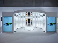 an exhibit room with several cell phones on the wall and in the background is a circular display area