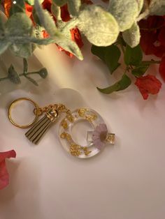 a glass keychain with a tassel hanging from it's center surrounded by flowers