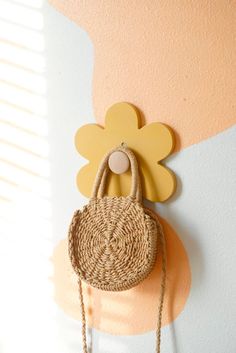 a handbag hanging on the wall with a flower shaped decoration attached to it's back