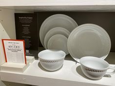 white dishes and plates on display in a store shelf with information about the price for them