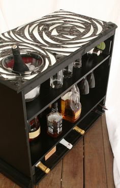 a black and white cabinet with liquor bottles on it's sides, sitting on a wooden floor