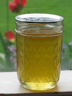 a jar filled with liquid sitting on top of a window sill next to flowers