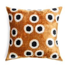 an orange and black pillow with white dots on the front, sitting on a white background