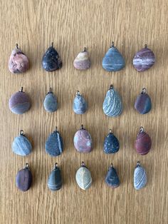 a collection of different sized and shaped rocks on a wooden surface with one hanging off the side