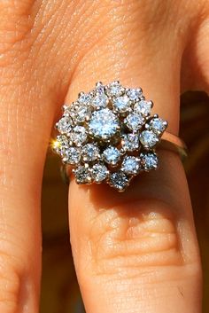 a woman's hand with a diamond ring on top of her finger and the other hand holding it