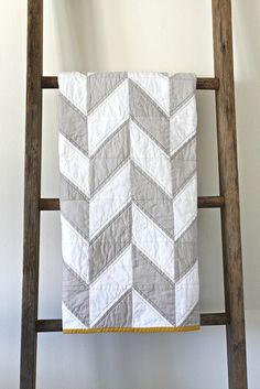 a white and gray quilt on a wooden ladder