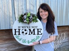 a woman holding up a sign that says if we're not home keep the ballpark