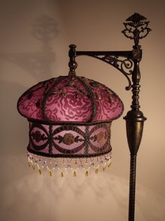 a lamp with a pink shade hanging from it's side next to a wall