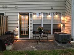 a patio with an air conditioner, table and chairs on the back porch area