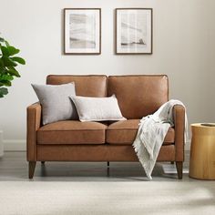 a brown leather couch sitting in a living room next to a potted plant