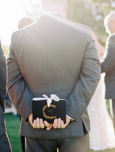 a man in a gray suit holding a black box with the letter c on it