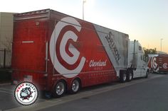 two large semi trucks parked next to each other on the side of the road in front of a building