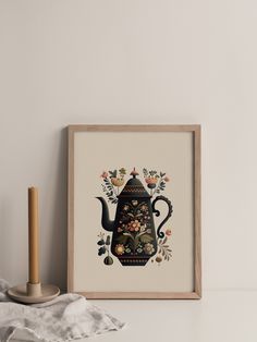 a teapot with flowers on it is next to a candle and some napkins