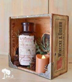 a wooden box with a candle and some other items in it that are on top of a table