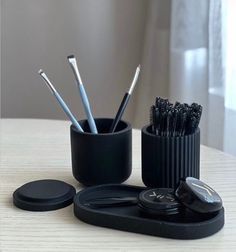 there is a black cup with toothbrushes and other items in it on the table