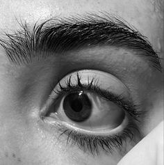 the eye of a person with very long hair on top of their head, looking up at the camera