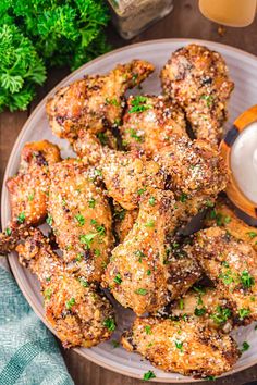 chicken wings on a plate with dipping sauce and parsley sprinkled around them