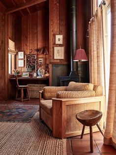 a living room filled with furniture and a fire place in the middle of a wooden paneled wall