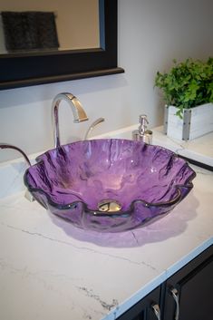 a purple glass bowl sink sitting on top of a counter