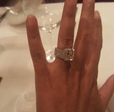 a woman's hand with a diamond ring on it, sitting at a table