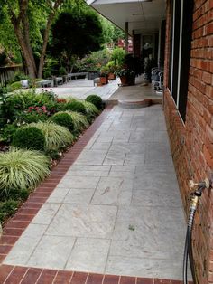 a brick walkway with plants and flowers on the side