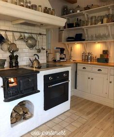 a stove top oven sitting inside of a kitchen next to a counter with pots and pans on it