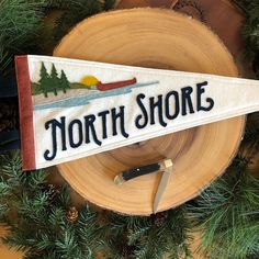 there is a sign that says north shore on the side of a pine tree branch