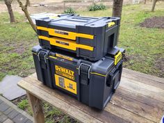 two dewly tool boxes sitting on top of a wooden bench in a park area