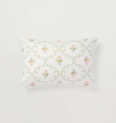 a white pillow with pink and blue flowers on the front, against a white background