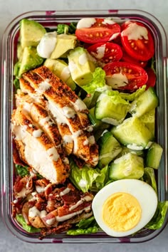 a salad with chicken, lettuce, tomatoes and hard boiled egg in it