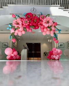 an archway decorated with balloons and flowers in the middle of a hallway at a hospital