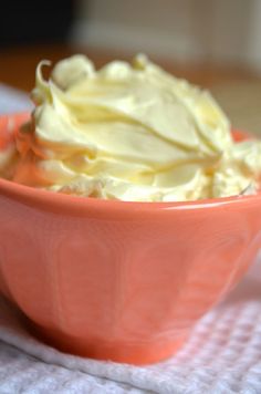 a pink bowl filled with whipped cream on top of a table