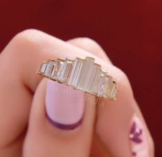 a woman's hand holding a gold ring with three baguettes on it