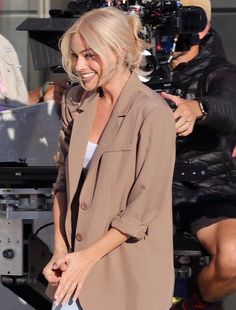 a woman is smiling as she stands in front of a camera and another man behind her