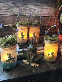 some jars with plants and fairy lights in them sitting on a table next to books