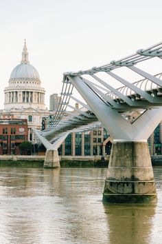 a bridge that is over water with buildings in the background