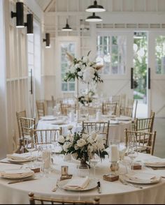 the tables are set with white flowers and place settings for an elegant dinner or reception