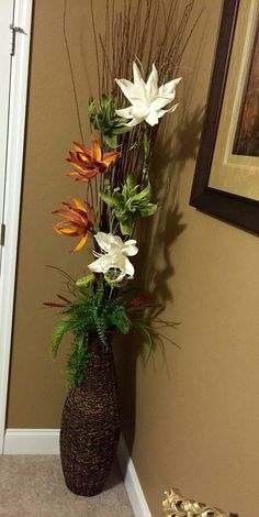 a tall vase filled with flowers next to a wall