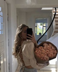 a woman taking a selfie while holding a bouquet of roses