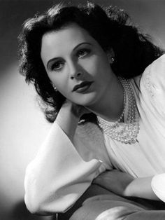 an old photo of a woman in white shirt and pearls on her collar, posing for the camera