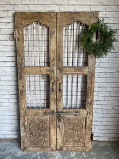 an old wooden door with iron bars on the front and side, in front of a white brick wall