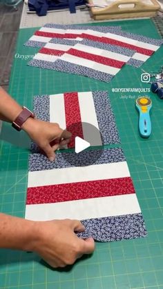 someone is cutting fabric with scissors on top of the quilting board and another person is using a pair of scissors to cut it