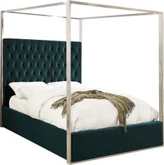 a bed with a green velvet headboard and white linens on the bottom side