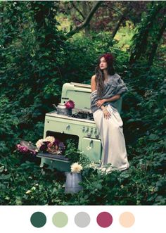 a woman sitting on top of an old stove in the middle of some bushes and trees