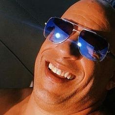 a man wearing sunglasses is smiling for the camera while laying on his back with an umbrella in front of him