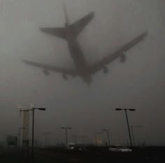 an airplane is flying in the air on a foggy day with lights and street lamps