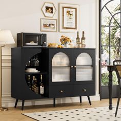 a black cabinet with wine glasses and bottles on it next to a dining room table