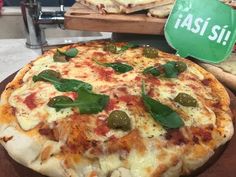 a pizza sitting on top of a wooden cutting board next to a green sign that says asia